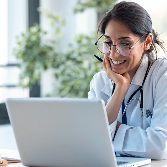 Smiling female doctor working with her laptop in the consultation.